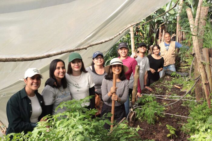 A group of participants at the event are surrounded by plants, smiling. 